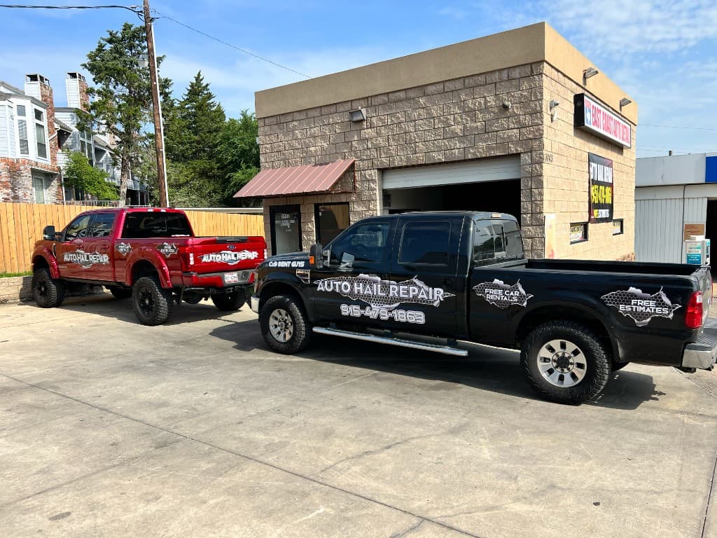 Red and black C & D Dent Guys branded trucks parked outside the repair shop